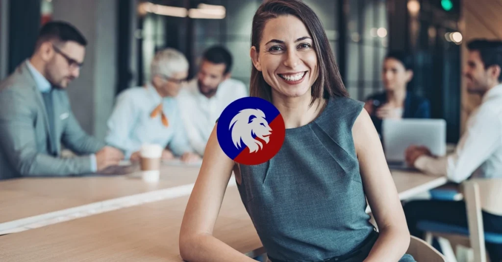 Professional woman standing apart from a business meeting smiling confidently at the camera.